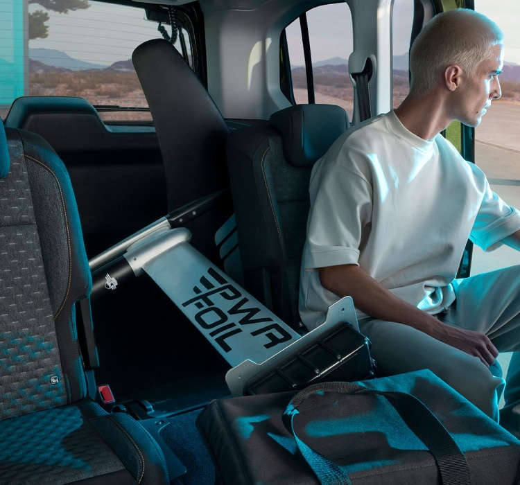 Чоловік сидить у салоні Peugeot e-Rifter разом з речами